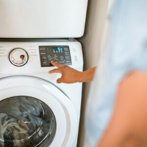 Hand selecting laundry options on a digital washing machine control panel indoors.