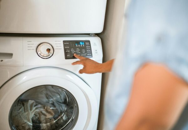 Hand selecting laundry options on a digital washing machine control panel indoors.